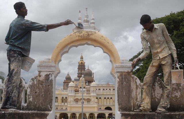 As part of the Dasara preparations, painters applying a coat of paint to the  compound wall of the Mysore Palace